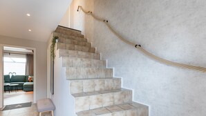 A staircase with beige tiles, a wooden handrail, and a rope handrail. - Ferienhaus "bräist Hus" in Bredstedt für bis zu 5 Personen (Bredstedt)