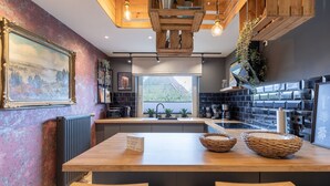 A modern kitchen with a wooden island, black tiled backsplash, and a large window. - Ferienhaus "bräist Hus" in Bredstedt für bis zu 5 Personen (Bredstedt)