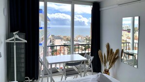 Habitación con balcón, una mesa y sillas, con vistas a la ciudad y al mar.