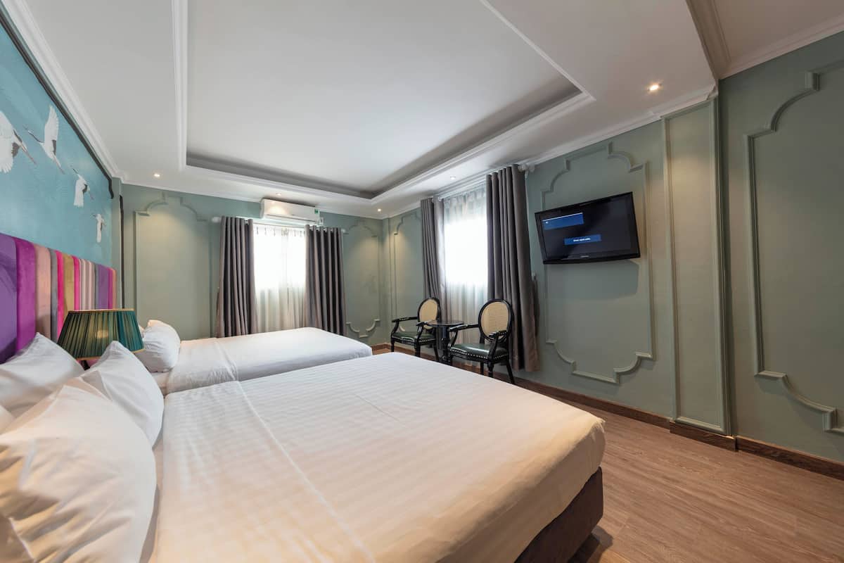 A hotel room with two beds, a television, a desk, and a chair.