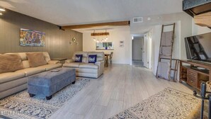 A modern living room with a sofa, ottoman, and a TV stand.