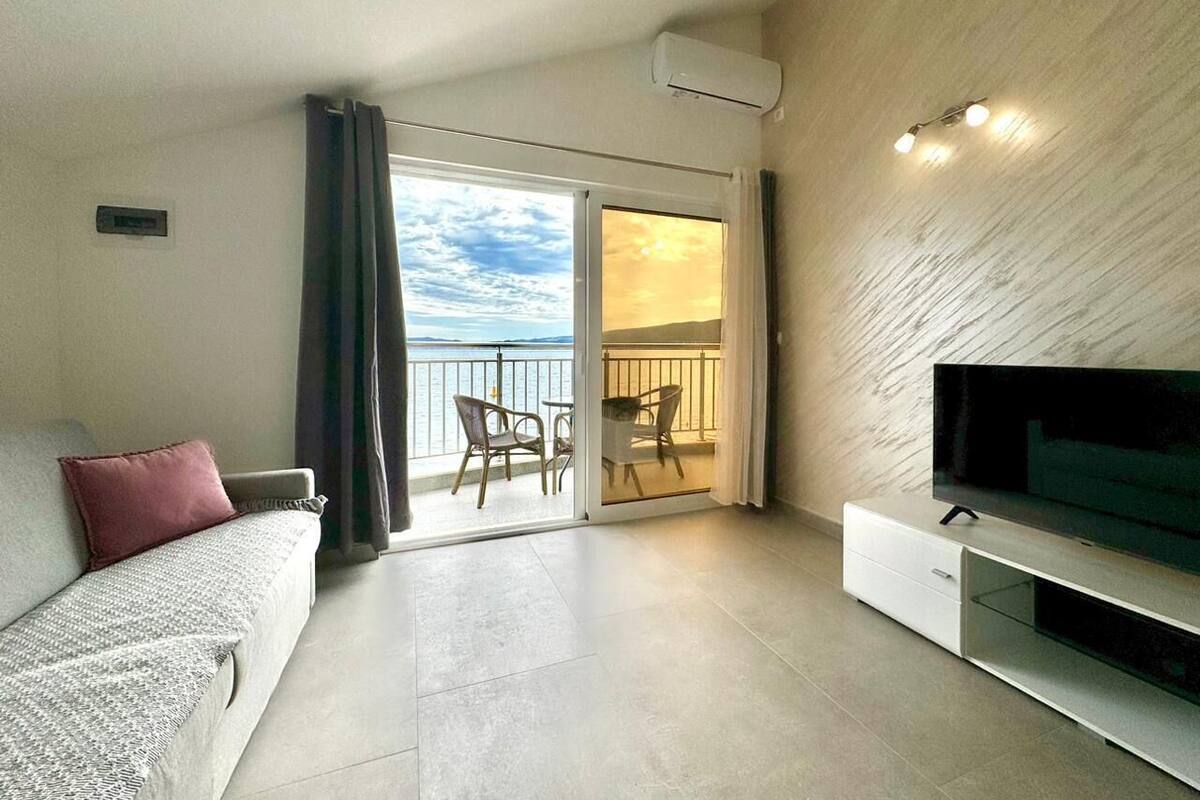Ein modernes Wohnzimmer mit einer Couch, einem Flachbildfernseher und einem Balkon mit Meerblick.