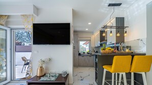 Une cuisine moderne équipée d’un téléviseur, de tabourets de bar et d’un coin repas avec une table et des chaises.