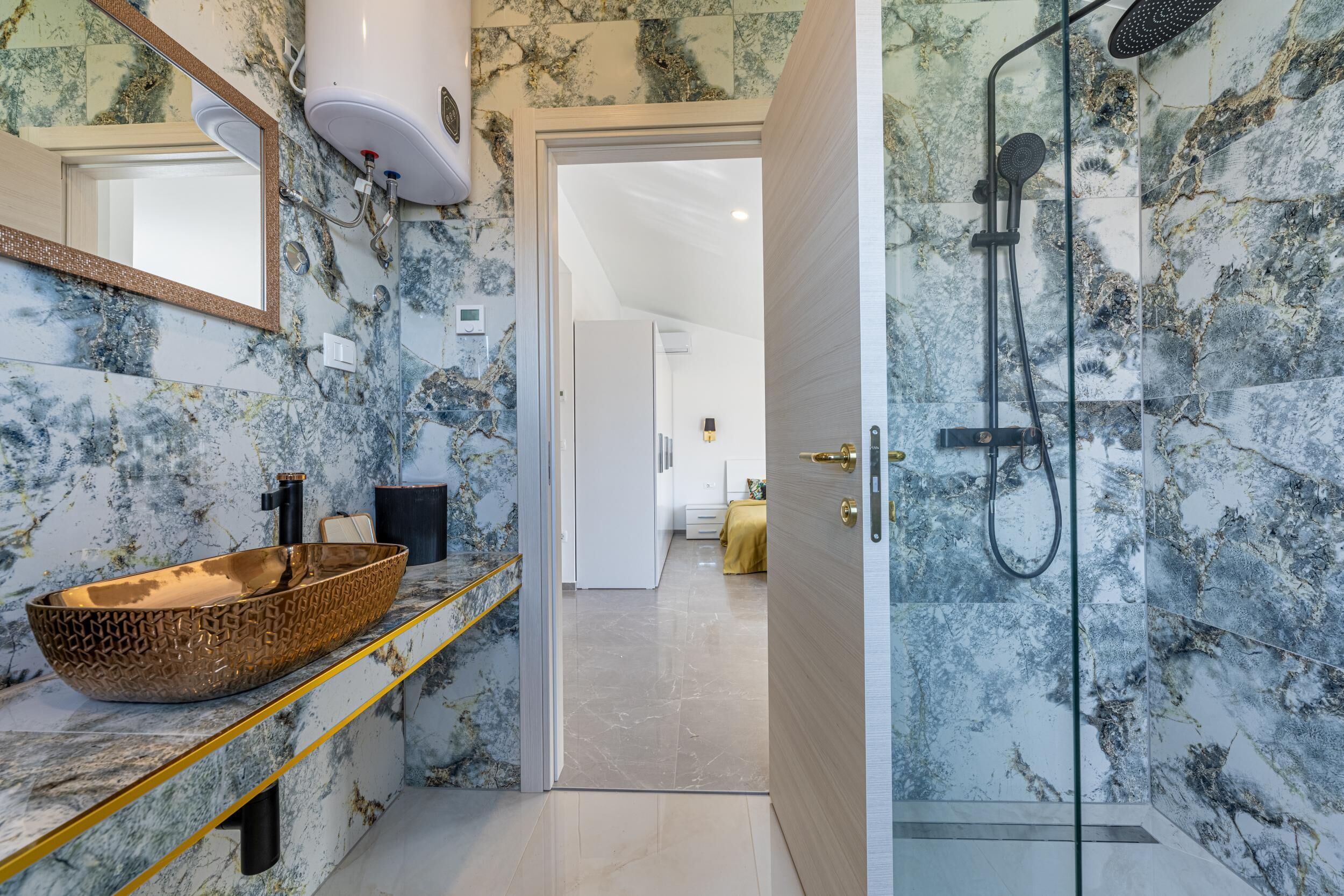 Une salle de bain avec un lavabo en marbre, une douche et un miroir.