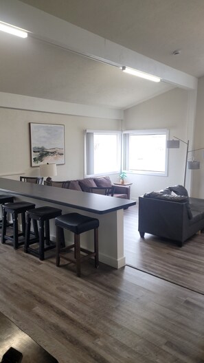 Een moderne keuken met een centraal eiland, barkrukken, een bank en een eettafel.