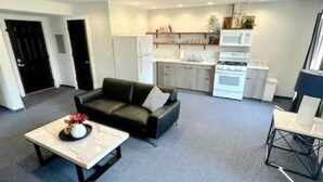 Een moderne woonkamer met een bank, een salontafel en een eethoek met een stoel.
