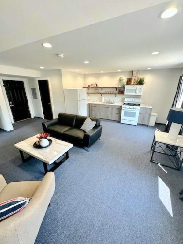 A modern living room with a sofa, coffee table, and a dining area with a chair.