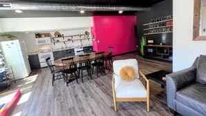 A modern kitchen with a dining area, a bar, and a seating area with a couch and a chair.