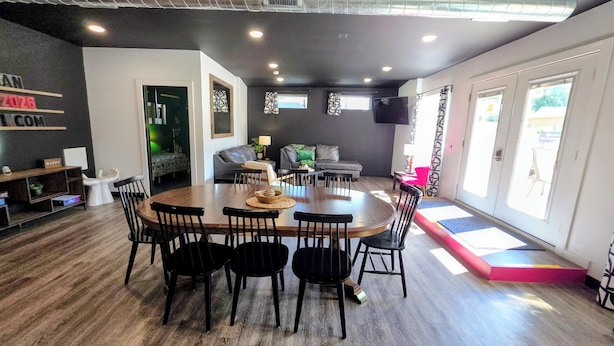 A modern living room with a dining area, a sofa, a TV, and a staircase leading to an outdoor area.