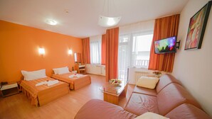 A hotel room with two beds, a sofa, a coffee table, and a TV. - Flora Residence Daisy (Samokov)