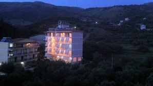 Hotel de vários andares com um átrio central e varandas, rodeado por colinas.