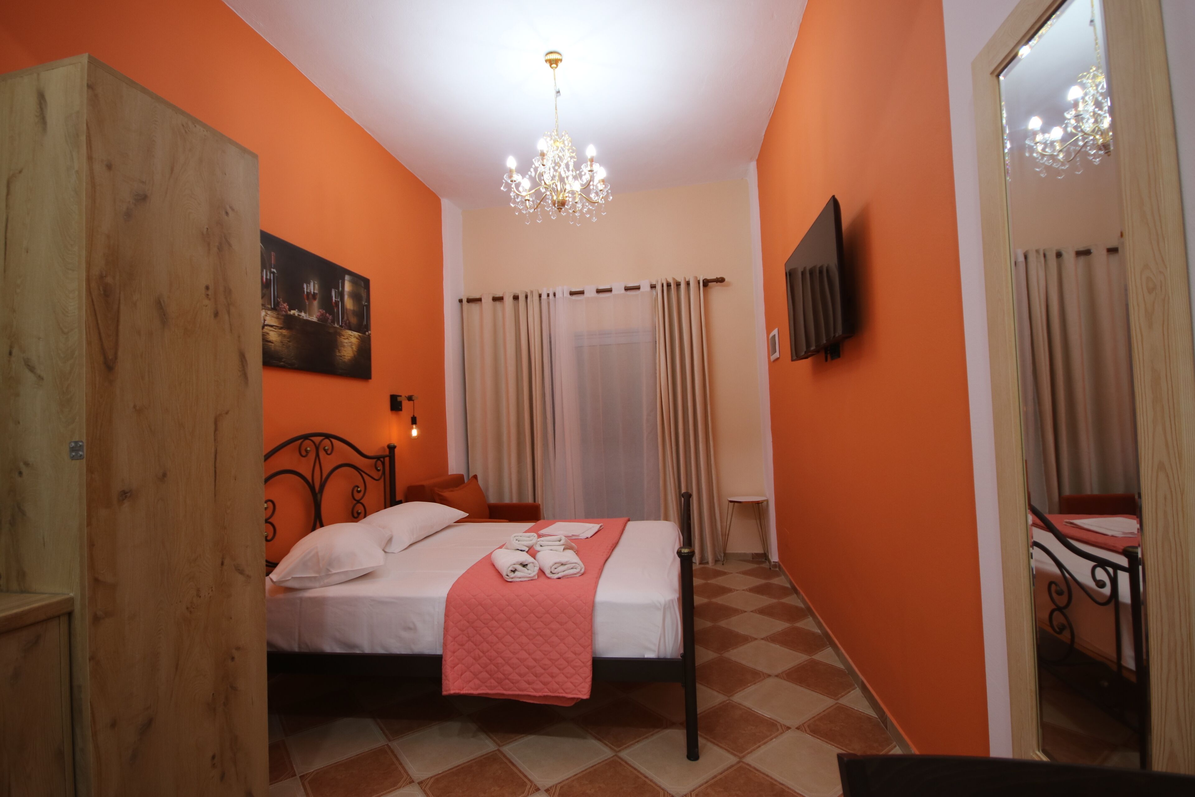 Una habitación de hotel con cama, un armario de madera, un candelabro y un espejo.