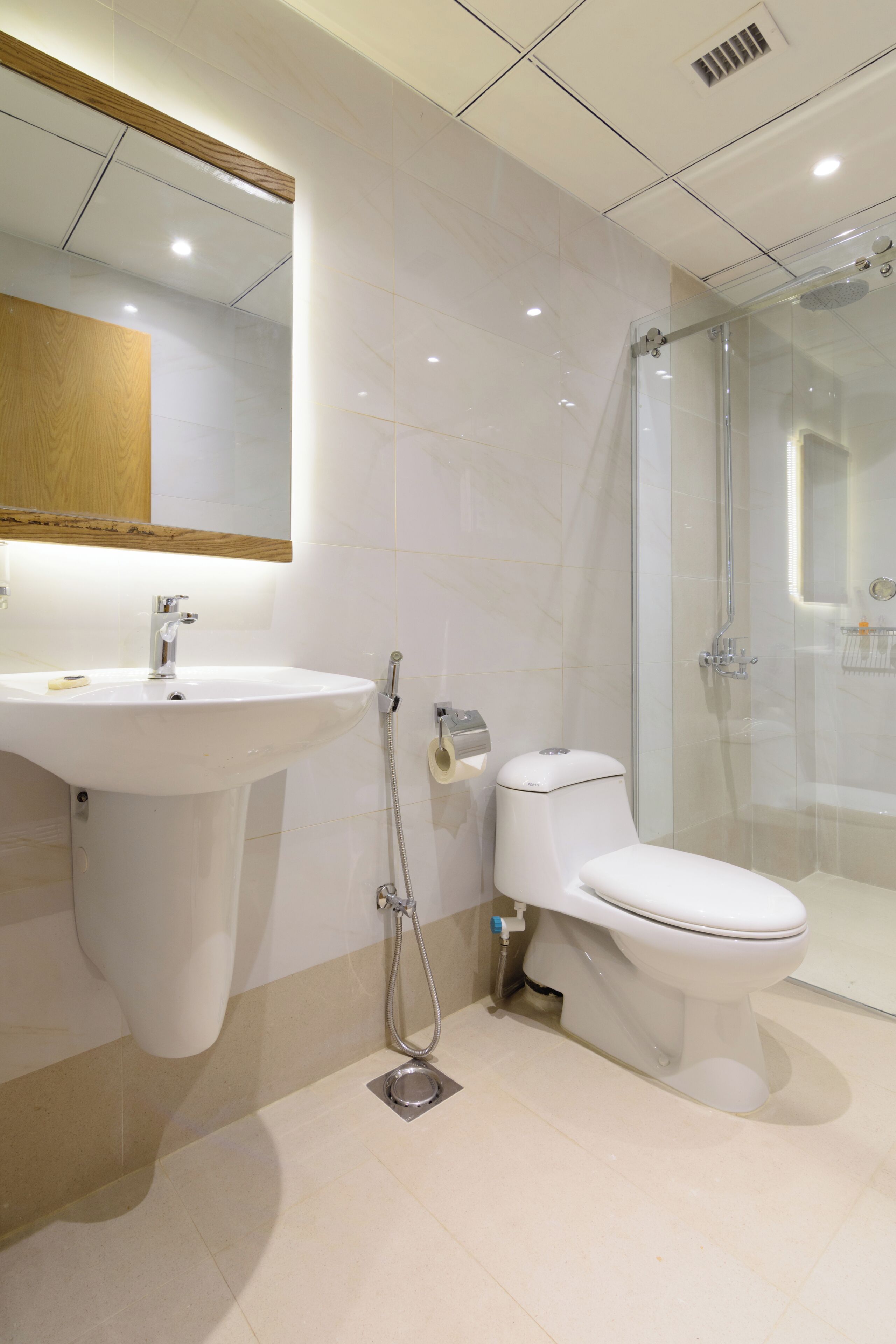 Un baño moderno con lavamanos, inodoro y ducha con mampara de vidrio.