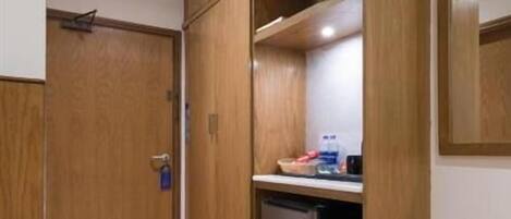 Una habitación compacta con armarios de madera, un refrigerador empotrado y una pequeña mesa.