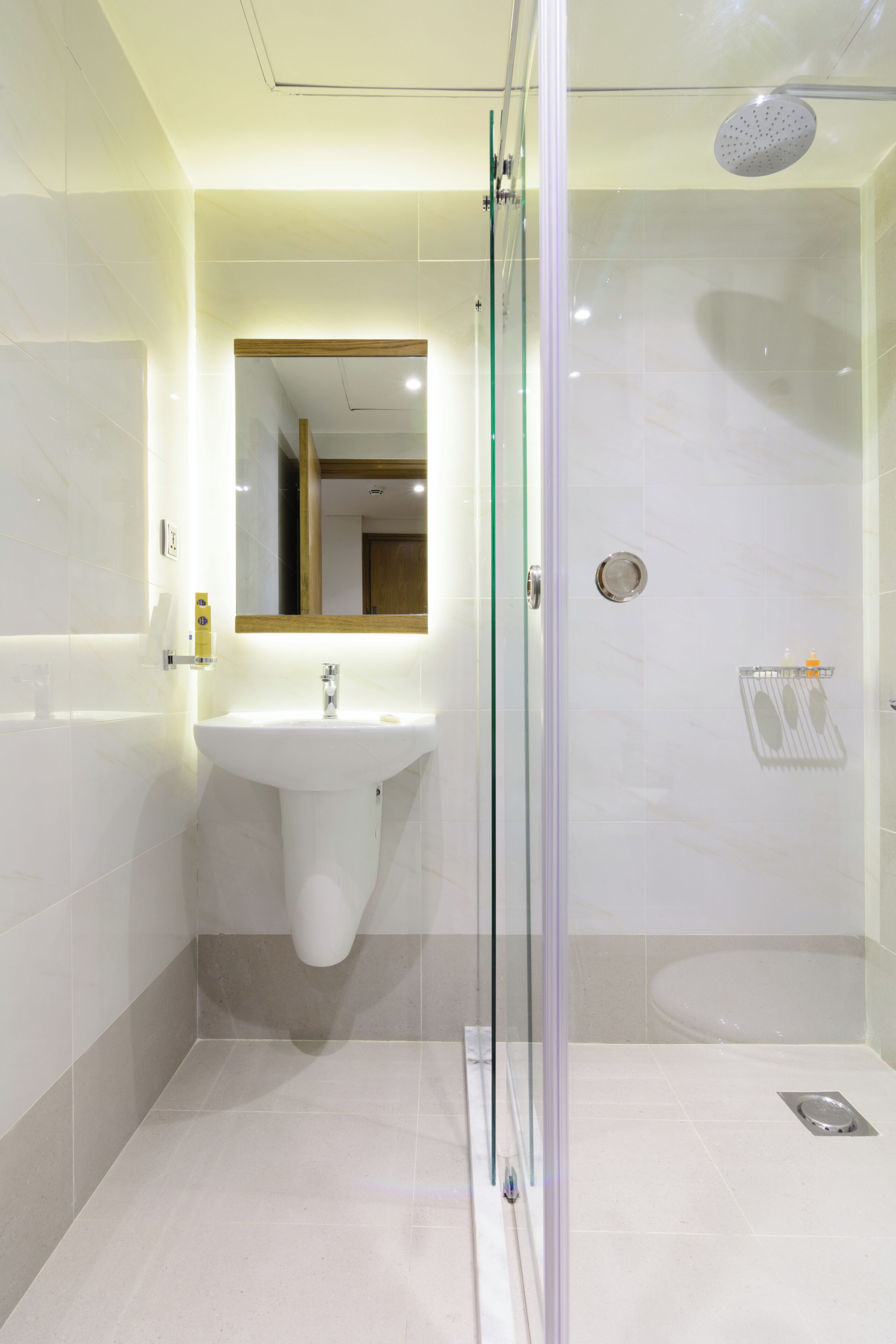 Un baño moderno con ducha envuelta en vidrio, un lavabo y un espejo.