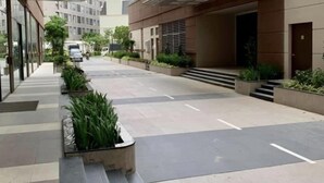 A modern building with a covered walkway, potted plants, and a clear sky.