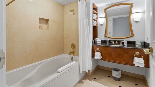 Une salle de bain moderne équipée d’une baignoire, d’une douche, d’un meuble-lavabo avec miroir et d’un porte-serviettes.