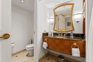A bathroom with a white toilet, a wooden vanity with a gold faucet, and a large mirror with a gold frame.