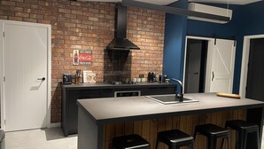 Een moderne keuken met een bakstenen muur, een groot eiland met barkrukken, en een bord waarop Coca-Cola wordt aangeboden.