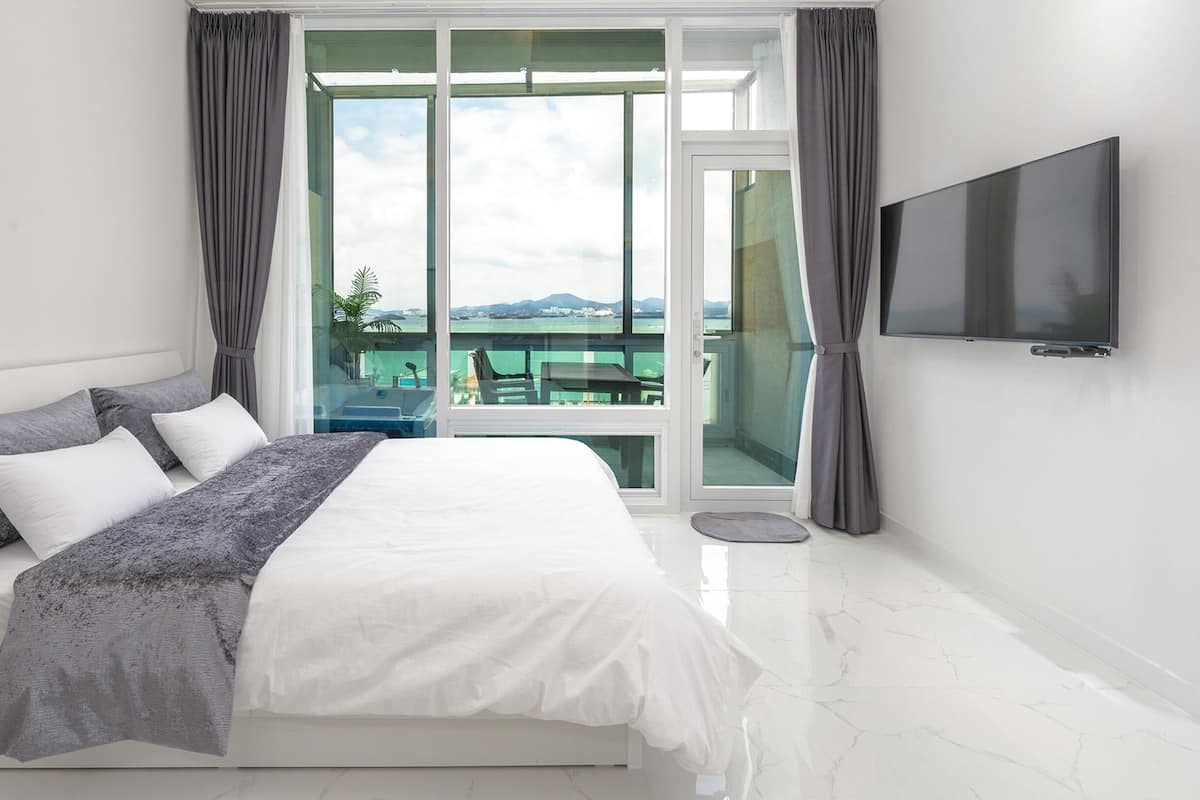 Een moderne slaapkamer met een groot bed, een flatscreen televisie en een balkon met uitzicht.