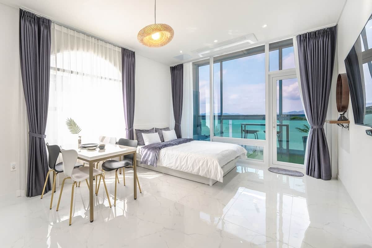 Een moderne slaapkamer met een groot bed, een eettafel en een balkon met uitzicht.