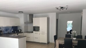 Eine moderne Küche mit weißen Schränken, einer zentralen Kochinsel und einem Essbereich mit Tisch und Stühlen.