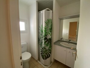 Ein Badezimmer mit Toilette, einer Duschkabine, einem Waschbecken und einem Spiegel.