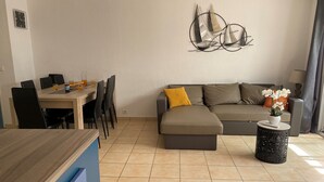 Ein modernes Wohnzimmer mit einem Ecksofa, einem Esstisch mit Stühlen und einer Wanddekoration.