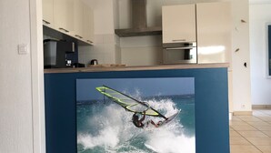 Eine Küche mit weißen Schränken, einer blauen Akzentwand und einem großen Bild eines Windsurfers auf einer Welle.