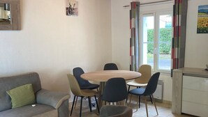 Ein modernes Wohnzimmer mit einem grauen Sofa, einem runden Holztisch und sechs Stühlen.