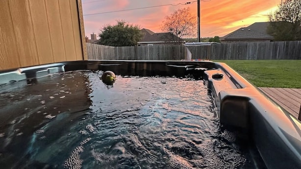Un bain à remous avec une terrasse en bois et une vue sur le coucher du soleil.