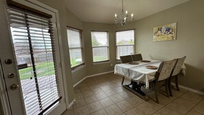 Un coin repas avec une table dressée pour quatre personnes, un lustre et un tableau accroché au mur.