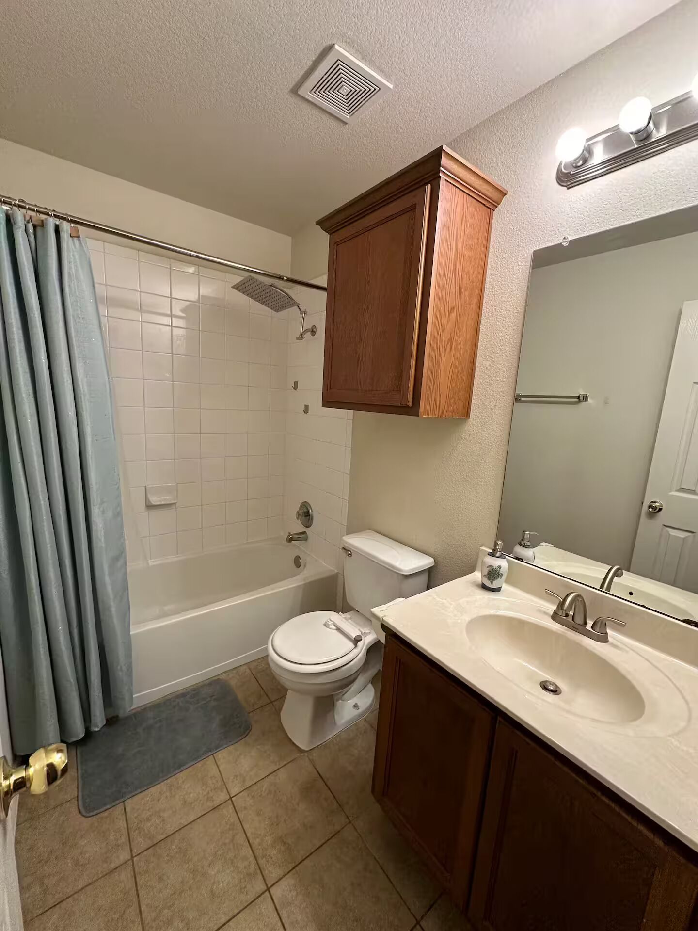 Et badeværelse med bruser, toilet, vask og skab.