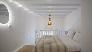 Un dormitorio con cama, lámpara colgante y ventana circular.