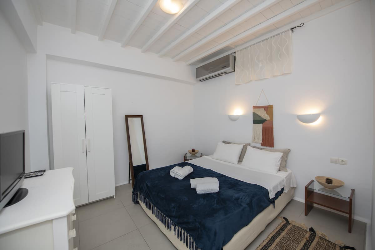 A bedroom with a bed, bedside table, and a TV.