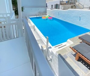 Una piscina sul tetto con acqua cristallina, circondata da pareti e recinzione bianche.