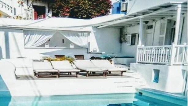 Zona de piscina con sillones de descanso y un área de estar techada.