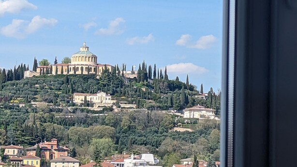 A view of a hillside with a prominent building with a dome and columns, surrounded by trees and other buildings.