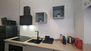 A modern kitchen with a black range hood, a built-in microwave, a sink, and a coffee maker.