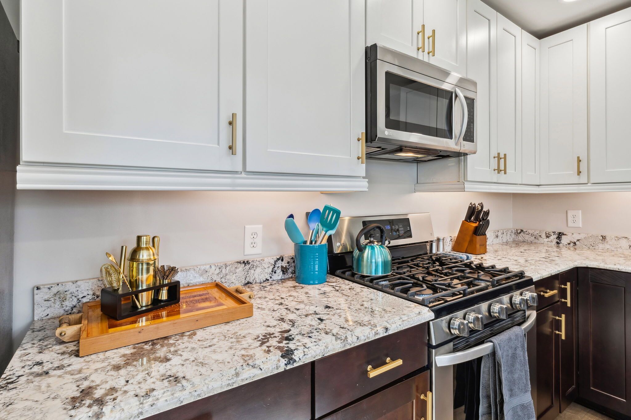 A kitchen with white cabinets, a stainless steel microwave, a gas stove, and a granite countertop.