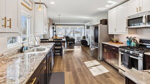 A modern kitchen with white cabinets, stainless steel appliances, and a marble countertop. - Hilltop Lakehouse - Free Kayaks, Deck, Hot Tub , Pet Friendly (Akron)