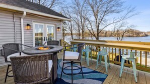A deck with wicker chairs and a table, overlooking a body of water. - Hilltop Lakehouse - Free Kayaks, Deck, Hot Tub , Pet Friendly (Akron)