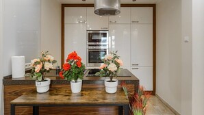 A modern kitchen with white cabinets, a stainless steel oven, and a wooden countertop with three potted plants. - Apartment in Platinum Tower FV in Warsaw (Warszawa)