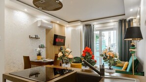A modern kitchen with a built-in stove, a sink, and a dining area with a table and chairs. There is a television mounted on the wall displaying the Netflix logo. - Apartment in Platinum Tower FV in Warsaw (Warszawa)