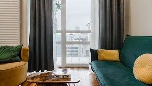 A living room with a sofa, a coffee table, and a window with curtains. - Apartment in Platinum Tower FV in Warsaw (Warszawa)