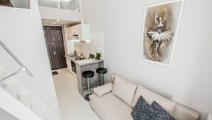 Une cuisine moderne avec des meubles blancs, un îlot central et deux tabourets de bar.