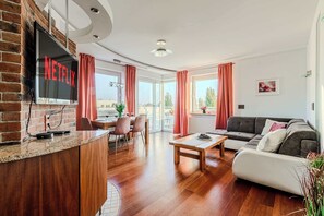 Una sala de estar moderna con un televisor de pantalla plana, un sofá, una mesa de centro y un comedor con sillas.