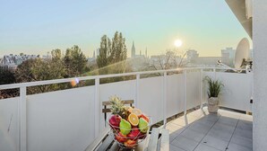 Ein Balkon mit Obstkorb, Topfpflanze und Blick auf die Stadtlandschaft.