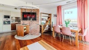 Eine moderne Küche mit Backsteinwand, ein Essbereich mit rosafarbenen Stühlen und ein großes Fenster mit Vorhängen.
