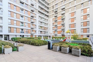 A multi-story residential building with balconies, a playground, and a landscaped courtyard.
